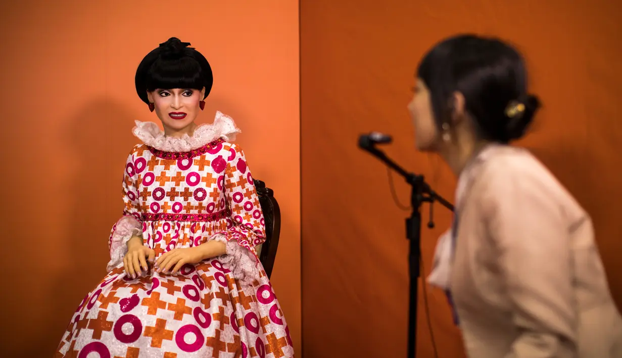 Seorang wanita berbicara dengan robot android 'totto' yang dimodelkan membentuk karakter salah satu bintang televisi terkenal Jepang, Tetsuko Kuroyanagi, saat dipamerkan selama World Robot Summit di Tokyo, 18 Oktober 2018. (Behrouz MEHRI/AFP)