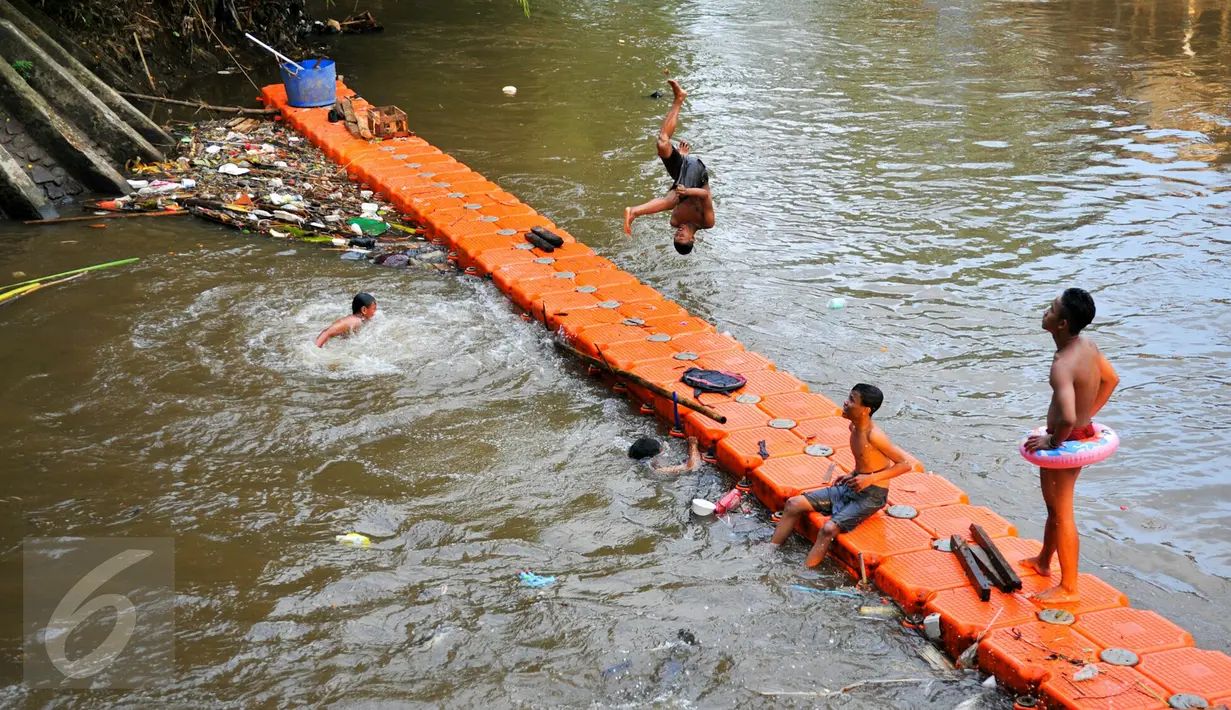 Anak-anak bermain di aliran Sungai Ciliwung, Jakarta, Rabu (18/5/2016). Meski belum terlalu bersih, seorang anak terlihat melompat untuk berenang di sungai tersebut. (Liputan6.com/Yoppy Renato)