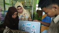 Dicky dan Haya, siswa MTSN 8 Sragen Kalijambe Sragen didampingi Kepala Sekolah Muawanatul Badriyah memeragakan cara kerja ATM Pembagi Sembako. (Foto: Liputan6.com/joglosemarnews.com/Wardoyo)