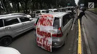 Sebuah spanduk terpampang saat ratusan sopir taksi online memarkir mobilnya di Jalan Medan Merdeka Barat, Jakarta, Rabu (14/2). Para pengemudi menolak Permenhub Nomor 108 karena dianggap memberatkan. (Liputan6.com/Arya Manggala)