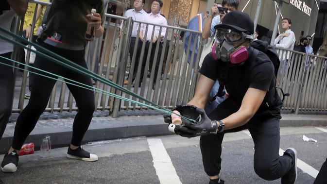 Para pengunjuk rasa menggunakan ketapel mencoba menembak saat demonstrasi di Hong Kong (11/11/2019). Ketapel hingga panahan digunakan para demonstran Hong Kong sebagai senjata saat unjuk rasa yang telah berlangsung selama lima bulan. (AP Photo/Kin Cheung)