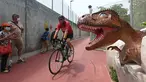 Pengendara sepeda bersepeda di sepanjang "Changi Jurassic Mile" jalur rekreasi dengan jajaran model dinosaurus seukuran aslinya di Singapura (13/10/2020). Atraksi rekreasi baru dengan pameran dinosaurus yang menghubungkan terminal Bandara Changi 4 dan taman East Coast. (AFP/Roslan Rahman)