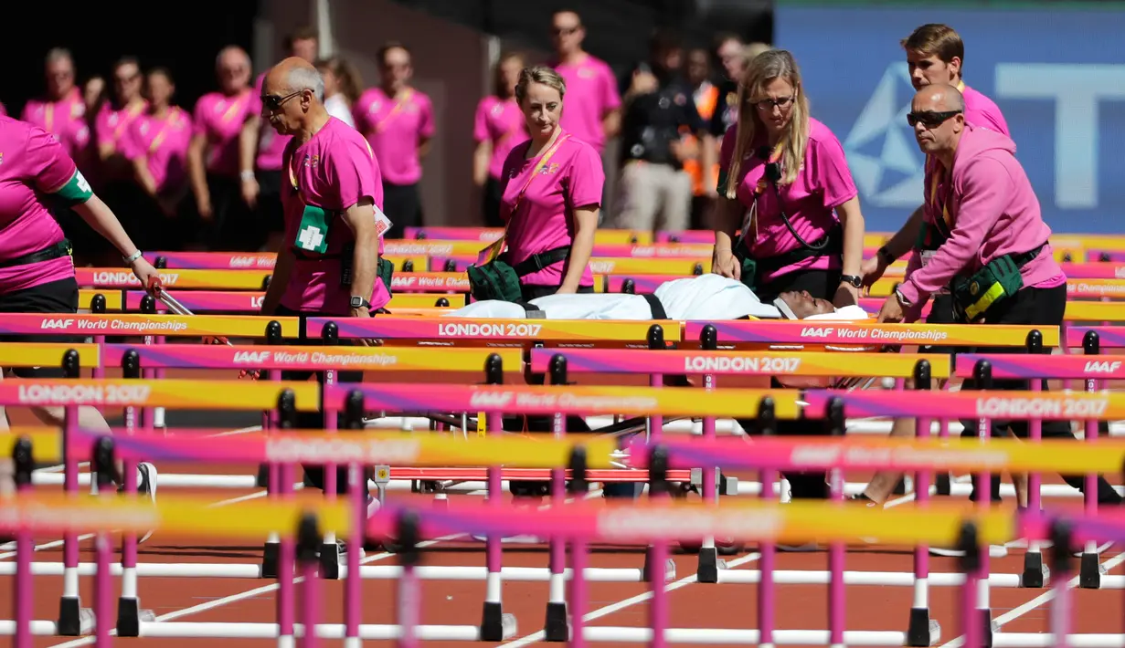 Petugas medis menandu atlet Trinidad dan Tobago, Deborah John yang cedera usai terjatuh saat melewati rintangan kelima dalam cabang lari halang rintang 100 meter putri Kejuaraan Atletik Dunia di Stadion London, Inggris (11/8). (AP Photo/Matt Dunham)