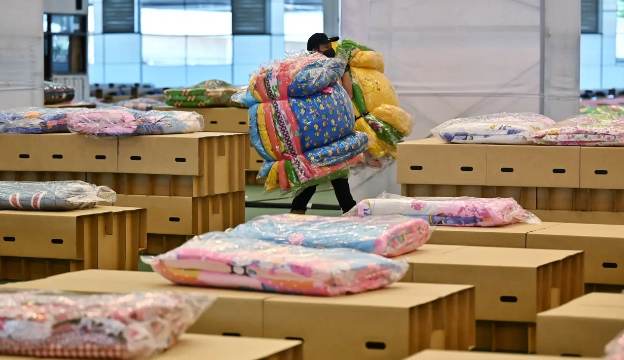 Pekerja menyiapkan kasur dan selimut untuk tempat tidur kardus di rumah sakit lapangan Covid-19 di dalam gudang Bandara Internasional Don Mueang di Bangkok, Selasa (27/7/2021). Thailand menghadapi rekor jumlah kasus virus corona di tengah kampanye vaksinasi yang lambat. (Lillian SUWANRUMPHA/AFP)