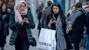 Pembeli memainkan ponsel sambil berjalan membawa kantong belanjaan di Oxford Street, London pada Sabtu (22/12). Menjelang natal, Oxford Street yang merupakan salah satu pusat perbelanjaan di jantung Kota London keramaiannya meningkat. (NIKLAS HALLE'N/AFP)