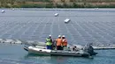 Petugas menggunakan perahu karet memeriksa panel surya fotovoltaik mengapung di kompleks pembangkit listrik O'Mega1 di Piolenc, Prancis selatan (30/7/2019). Pembangkit listrik tenaga surya (PLTS) mengapung pertama di Eropa ini akan beroperasi pada September 2019. (AFP Photo/Gerard Julien)