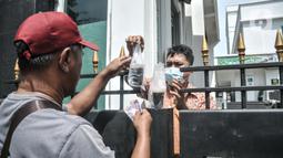 Pegawai saat membeli makanan melalui salah satu pagar gedung PN Jakarta Barat, Kamis (27/1/2022). Penutupan dimulai pada 27-31 Januari 2022 dan akan dibuka kembali pada 2 Februari 2022. (Merdeka.com/Iqbal S. Nugroho)