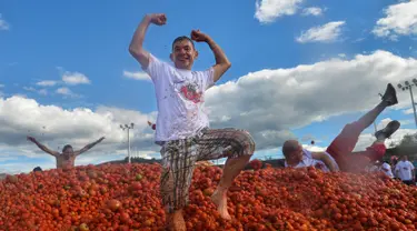 Peserta berdiri di atas gundukan tomat saat Festival Tomatina di Sutamarchan, Boyaca, Kolombia, Minggu (2/6/2019). Perang tomat ini digelar selama tiga hari berturut-turut. (Diana SANCHEZ/AFP)