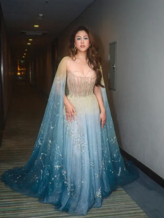 Penampilan bak princess Sherina Munaf pakai dress megah. Detail dress dengan cape dan rok yang flowy menjuntai hingga ke lantai bernuansa biru gradasi membuat penampilan Sherina bak ratu es. [Foto: Instagram/sherinamunaf]