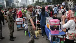 Satpol PP DKI Jakarta menertibkan PKL yang berdagang di kawasan Car Free Day, Bundaran HI, Jakarta, Minggu (20/1). Penertiban dilakukan karena telah membuat ketidaknyamanan bagi para pengunjung CFD yang ingin berolahraga. (Liputan6.com/Faizal Fanani)