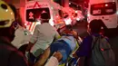 Pekerja darurat membawa orang yang terluka dengan tandu setelah jembatan layang untuk kereta metro ambruk di Mexico City, Senin (3/5/2021). Setidaknya 13 orang tewas dan puluhan lainnya luka-luka akibat kecelakaan kereta metro di ibu kota Meksiko tersebut. (Pedro PARDO/AFP)