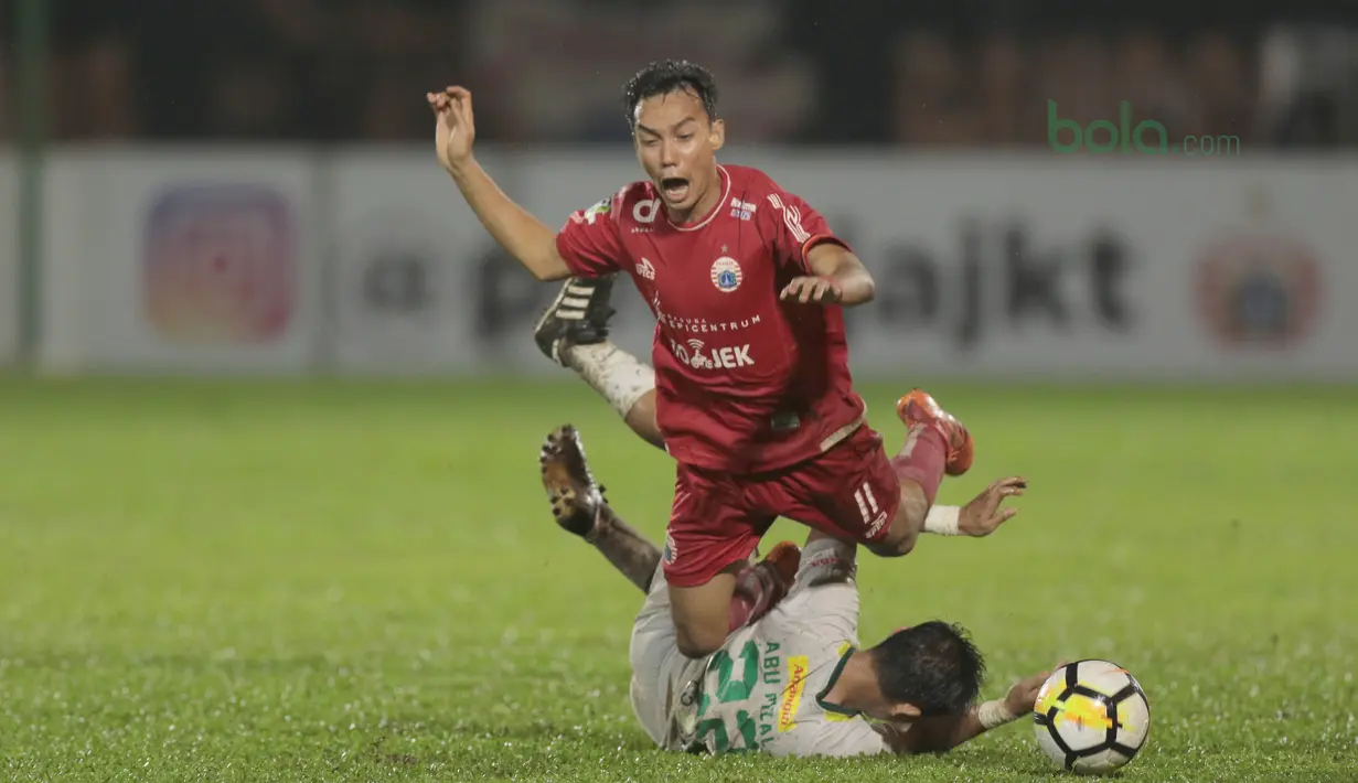 Pemain Persija Jakarta, Novri Setiawan jatuh saat dijegal pemain Persebaya, Abu Rizal (bawah) pada laga Gojek Liag 1 bersama Bukalapak di Stadion PTIK, Jakarta (26/6/2018). Persija dan Persebaya bermain imbang 1-1. (Bola.com/Nick Hanoatubun)