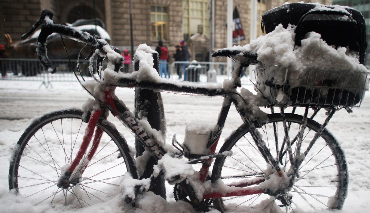 Sebuah sepeda tertutup salju di trotoar Broadway, New York, Selasa (14/3). Badai salju yang terjadi di sejumlah wilayah Amerika Serikat memaksa ribuan jadwal penerbangan dibatalkan dan sekolah-sekolah terpaksa ditutup sementara. (DON EMMERT/AFP)