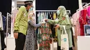 Chief Marketing Officer LinkAja Wibawa Prasetyawan (kiri) dan Direktur Departemen Ekonomi dan Keuangan Syariah Bank Indonesia, Ita Rulina (kanan) melihat baju muslim pada SEF ke-8 Tahun 2021 di JCC Senayan, Jakarta, Rabu (27/10/2021). (Liputan6.com/Fery Pradolo)
