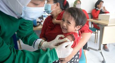 Perawat dibantu kader Posyandu menyuntikan vaksin campak, vaksin pentabio berisi vaksin DPT, Hepatitis B dan Haemophilus Influenzae dan Imunisasi Polio terhadap anak di RW 09, Kelurahan Pondok Benda, Tangerang Selatan, Senin (14/12/2020). (merdeka.com/Dwi Narwoko)