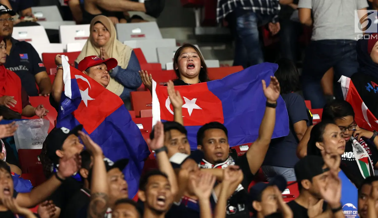 Suporter tim Johor Darul Takzim bernyanyi memberi semangat timnya saat melawan Persija pada lanjutan penyisihan Grup H Piala Asia 2018 di Stadion GBK, Jakarta, Selasa (10/4). Johor Darul Takzim kalah telak 0-4. (Liputan6.com/Helmi Fithriansyah)