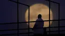 Seorang pria melihat bulan terbit dari menara observasi, di New Albany, Indiana Senin Senin (26/4/2021). Bulan ini adalah supermoon, artinya bulan tampak lebih besar dari rata-rata bulan purnama karena lebih dekat dari titik terdekat orbitnya ke Bumi. (AP Photo/Charlie Riedel)