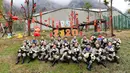 Penjaga memegang anak-anak panda yang lahir pada tahun 2019 saat berpose untuk foto untuk merayakan Tahun Baru Imlek di tempat perlindungan Shenshuping di Cagar Alam Nasional Wolong, provinsi Sichuan, Jumat (20/1/2020). Imlek 2020 jatuh pada 25 Januari mendatang. (STR / AFP)
