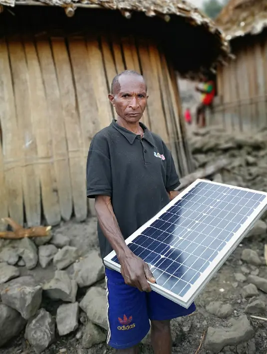 Warga membawa Lampu Tenaga Surya Hemat Energi (LTSHE) di Distrik Puldama, Kabupaten Yahukimo, Provinsi Papua. Kementerian ESDM membagikan secara gratis LTSHE kepada 1.085 KK di Distrik Puldama yang tersebar di delapan desa. (Liputan6.com/HO/Hadi M Juraid)