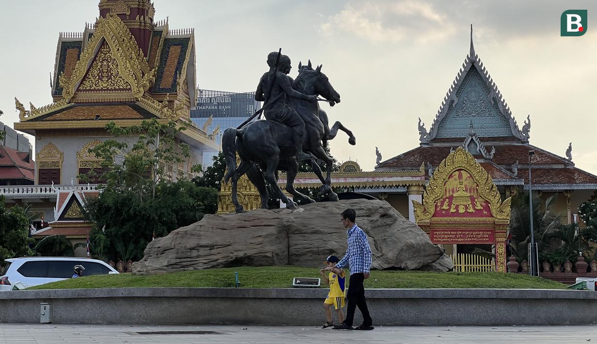 Warga melintasi Istana Kerajaan Kamboja yang terletak di kawasan kawasan Tonle Sap, Phnom Penh, Kamboja, Kamis (11/05/2023). Tonle Sap merupakan danau air tawar terbesar di Asia Tenggara. (Bola.com/Gregah Nurikhsani)