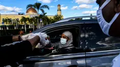 Seorang wanita menerima paket makanan buka puasa Ramadhan dari seorang sukarelawan Asosiasi Komunitas Muslim Miami dan Yayasan Lumba-Lumba Miami di Miami Gardens, Florida, Amerika Serikat, Selasa (27/4/2021). Distribusi makanan dilakukan secara drive thru. (CHANDAN KHANNA/AFP)