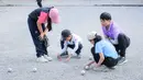 Beberapa anak memainkan olahraga Petanque di Lapangan Latih Dua Kompleks 700th Anniversary of Chiang Mai Stadium, Thailand, Kamis (11/12/2025). Petanque merupakan salah satu olahraga favorit bagi masyarakat Thailand. (Bola.com/Bagaskara Lazuardi)