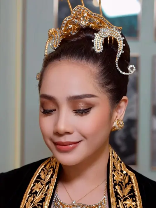 Wajah Nagita tampak dipulas dengan makeup flawless. Eyeshadow matte coklat dan shimmer bronze tampak diaplikasikan di kelopak matanya. Ditambah dengan bulu mata palsu natural yang membuat mata Nagita terlihat lebih tajam. [@raffinagita1717/@erniaredberry]
