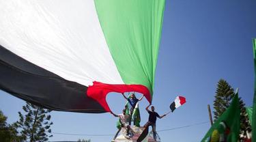 Warga Palestina membentang bendera negara mereka, bergembira menyambut rekonsiliasi antara Hamas dan Fatah