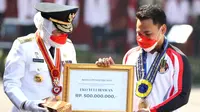 Eko Yuli Irawan mendapat tanda kehormatan dari Gubernur Jawa Timur, Khofifah Indar Parawansa, pada peringatan HUT ke-76 RI di Gedung Negara Grahadi Surabaya, Selasa (17/8/2021). (Bola.com/Aditya Wany)