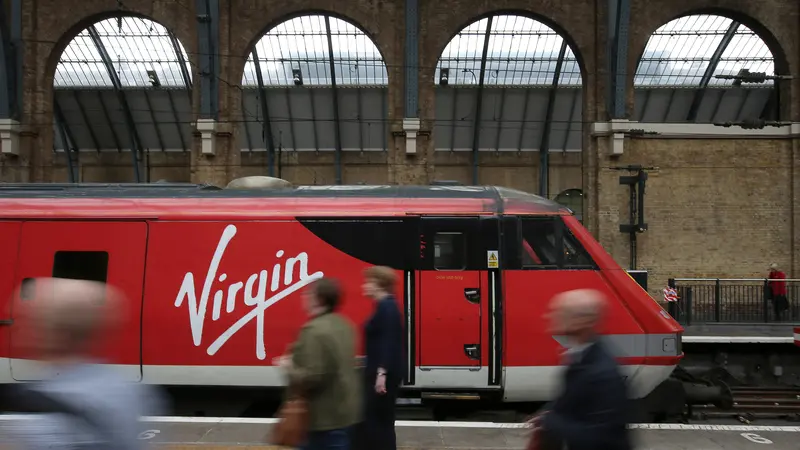 Penumpang kereta api melewati kereta yang dioperasikan oleh layanan jalur utama Virgin Trains East Coast berada di stasiun kereta London Kings Cross di London pada 16 Mei 2018.