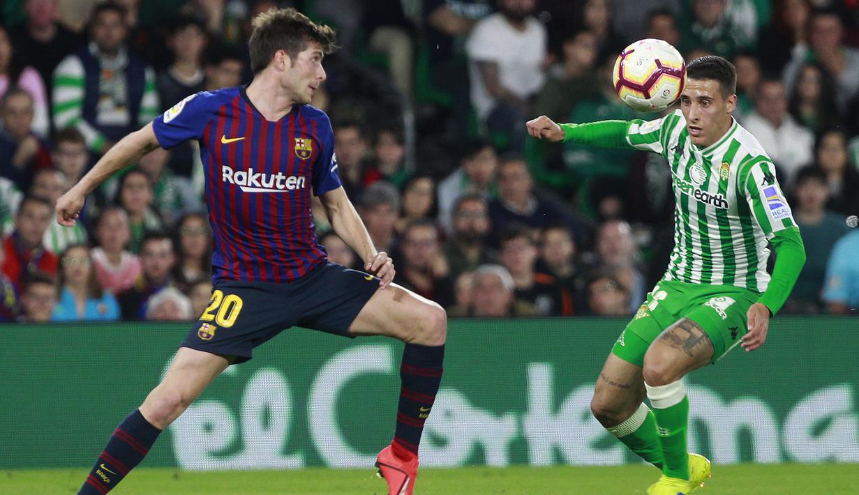 Pemain Real Betis, Tello Herrera, berebut bola dengan gelandang Barcelona, Sergi Roberto, pada laga La Liga 2019 di Stadion Benito Villamarin, Minggu (17/3). Barcelona menang 4-1 atas Real Betis. (AP/Miguel Morenatti)