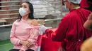 Seorang wanita menerima vaksin virus corona COVID-19 AstraZeneca di Denpasar, Bali, Sabtu (26/6/2021). Ratusan warga terlihat antusias mengikuti vaksinasi massal tersebut. (SONY TUMBELAKA/AFP)