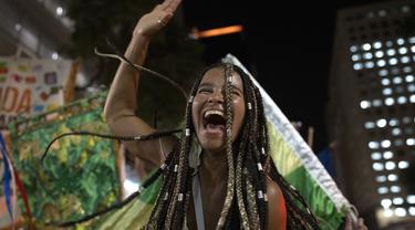 Seorang peserta pesta jalanan yang dikenal sebagai blocos, menari selama protes terhadap pembatasan oleh pejabat kota di Rio de Janeiro, Brasil (13/4/2022). Balai Kota telah melarang pesta jalanan selama perayaan Karnaval, yang tertunda hampir dua bulan karena pandemi. (AP Photo/Silvia Izquierdo)