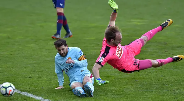 Lionel Messi (kiri) berusaha menjangkau bola dari adangan kiper Eibar, Marko Dmitrovic pada lanjutan La Liga Santander di Ipurua stadium,  Eibar, (17/2/2018). Barcelona menang 2-0. (AFP/Ander Gillenea)