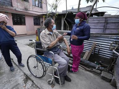 Seorang pria di kursi roda menyingsingkan lengan bajunya untuk vaksin COVID-19 di Quito, Ekuador, 26 Januari 2022. Brigade campuran dari pemerintah kota dan Kementerian Kesehatan mengunjungi lingkungan miskin untuk mendeteksi kasus COVID-19 dan melakukan vaksinasi. (AP Photo/Dolores Ochoa)