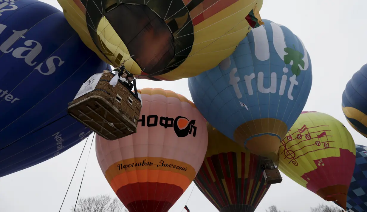 Pasangan pengantin berada di balon udara saat mengikuti Festival Love Cup 2016 di Jekabpils, Latvia (14/2). Sebanyak 50 pasangan pengantin dibagi dalam 27 balon udara terbang bersama mengikat janji cinta mereka. (REUTERS/Ints Kalnins)