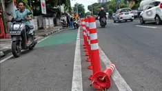 Pengendara bermotor melintas di samping stick cone pembatas jalur sepeda di Kawasan Jalan Penjernihan Jakarta, Sabtu (10/12/2022). Keadaan stick cone untuk pembatas jalur sepeda tersebut terlihat sudah rusak dan tidak terpasang dengan benar. (Liputan6.com/Angga Yuniar)