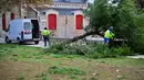 Para pekerja menebang pohon yang tumbang di depan salah satu menara La Rochelle di La Rochelle, Prancis barat tengah pada tanggal 2 November 2023, saat badai Ciaran menghantam wilayah tersebut. (YOHAN BONNET/AFP)