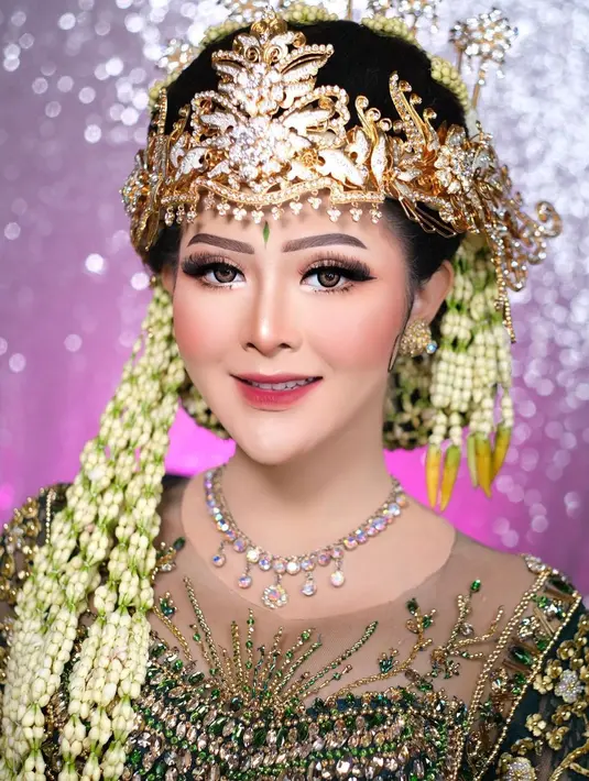 Sang MUA tampak mengaplikasikan complexion matte dan contour yang tegas untuk membuat wajah Bella lebih tirus. Alisnya dibingkai rapi, kemudian area kelopak matanya dipoles eyeshadow berwarna coklat dengan shimmer emas.  [Instagram/khadijahazzahra_makeup]