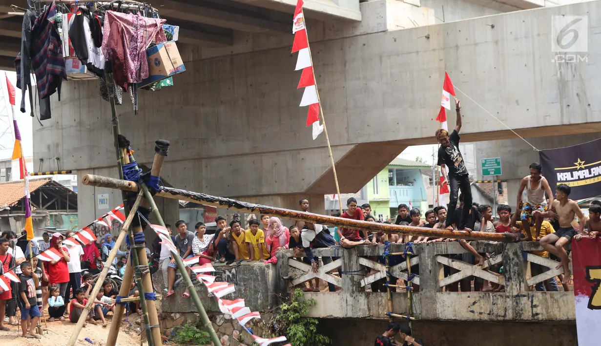 Warga bermain lomba jalan di atas batang pohon pinang di sekitar Kalimalang, Jakarta, Sabtu (17/8/2019). Beragam lomba permainan digelar warga untuk menyemarakkan HUT ke-74 Republik Indonesia. (Liputan6.com/Helmi Fithriansyah)
