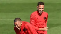 Pemain Paris Saint-Germain (PSG), Neymar (kanan) dan Kylian Mbappe (kiri) tertawa saat sesi latihan di Paris Barat, Prancis, Senin (17/9). PSG akan menghadapi Liverpool di Liga Champions pada 19 September 2018. (Anne-Christine POUJOULAT/AFP)