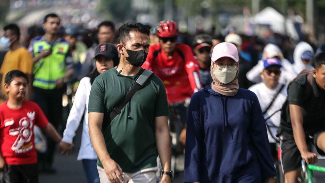 Masyarakat berolahraga menggunakan masker menikmati jalan santai saat car free day (CFD) di kawasan Bundaran HI, Jakarta, Minggu (13/8/2023).