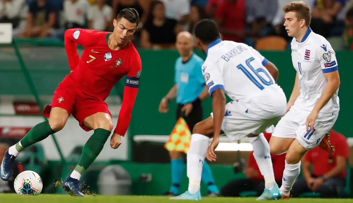 Megabintang timnas Portugal, Cristiano Ronaldo menggiring bola melewati pemain timnas Luksemburg Leandro Barreiro Martins dan Florian Bohnert dalam lanjutan Kualifikasi Piala Eropa 2020 di Estadio Jose Alvalade, Jumat (11/10/2019). Portugal meraih kemenangan 3-0 atas Luksemburg. (AP/Armando Franca)