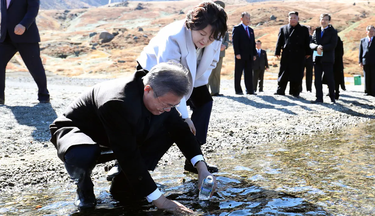 Presiden Korsel Moon Jae-in ditemani istrinya, Kim Jung-sook memasukkan air kawah ke dalam botol di Gunung Paektu, Korut, Kamis (20/9). Gunung ini menjadi propaganda untuk melegitimasi tiga generasi pemerintahan Kims. (Pyongyang Press Corps Pool via AP)