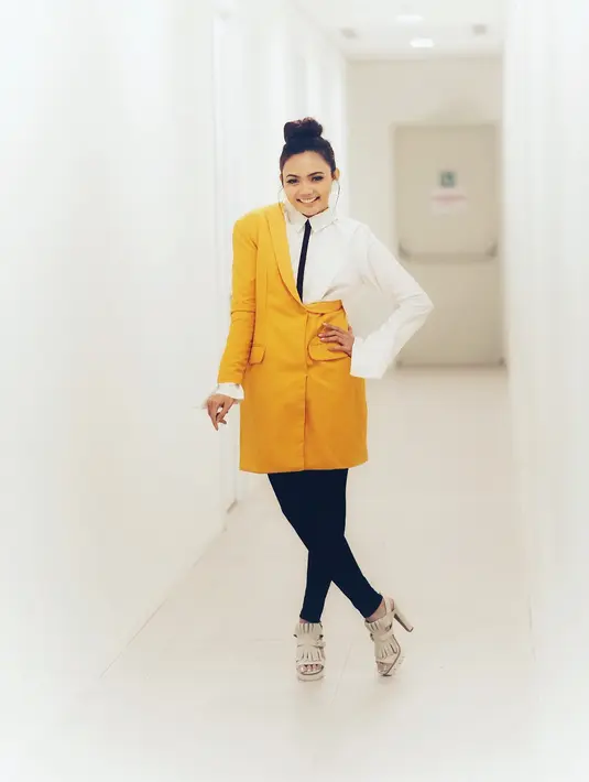 Nah, unik banget kan model busana Rina yang satu ini? Model long blazer ini merupakan paduan blazer berwarna kuning, dengan kemeja putih yang berdasi. Makin menarik, dengan model rambut bun hairnya. (Instagram/rinanose16)