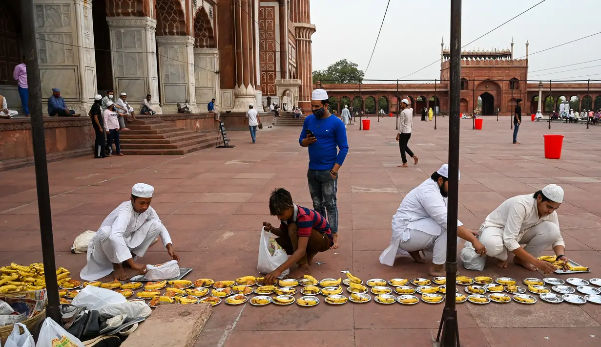 Relawan menyiapkan piring makanan untuk umat Muslim saat mereka berbuka puasa di Masjid Jama pada hari pertama bulan suci Ramadhan, di New Delhi (14/4/2021). Masjid ini didirikan oleh Kaisar Mogul, Syah Jehan, yang juga membangun Taj Mahal. (AFP/Prakash Singh)