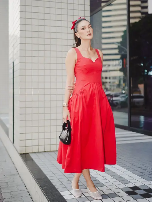 Penampilan tak kalah manis dengan pancaran aura luar biasa dari Luna Maya. Ia mengenakan dress midi berwarna merah tanpa lengan, dengan mini bag hitam, dan alas kaki putih. Rambutnya ditarik ke belakang dan dikuncir kuda tinggi mengenakan pita merah. [Foto: Instagram/lunamaya]