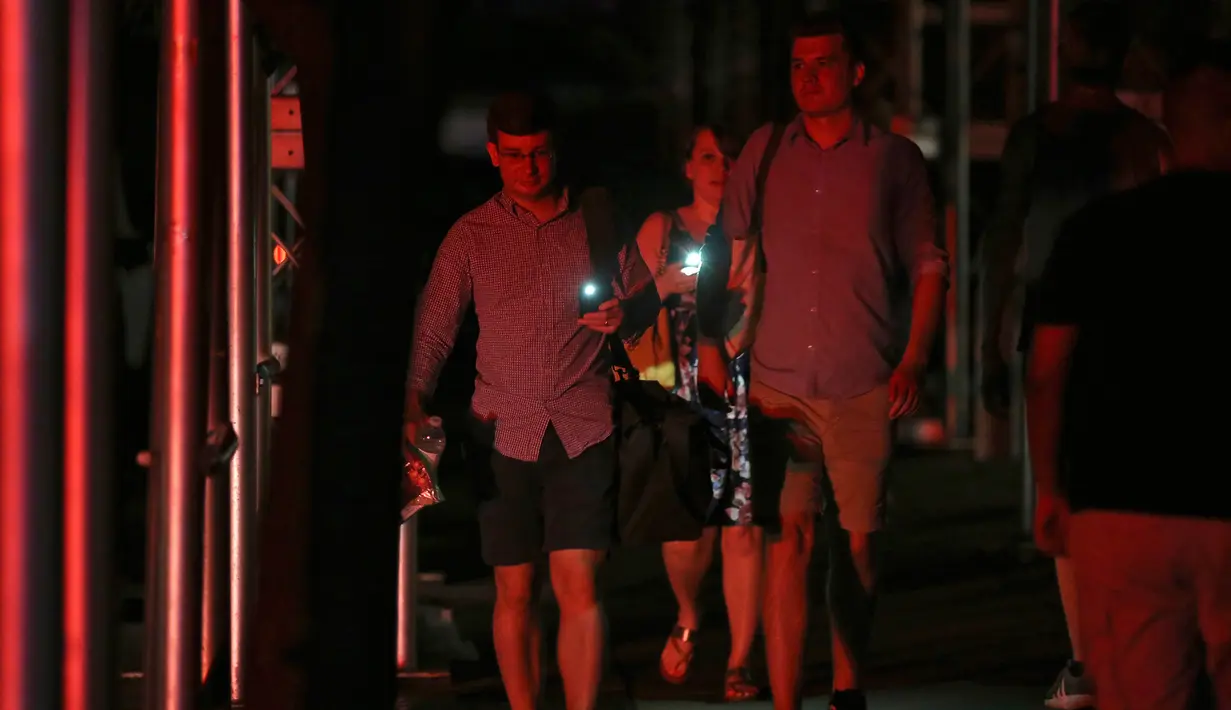 Pejalan kaki menggunakan ponsel mereka sebagai lampu senter selama pemadaman listrik di New York, AS, Sabtu (13/7/2019). Pemadaman listrik ini tentu saja membuat kacau New York. (AP Photo/Michael Owens)