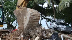 Alat berat melakukan evakuasi bangunan yang hancur akibat terjangan tsunami Selat Sunda di Carita, Banten, Selasa (25/12). Akibat tsunami yang melanda kawasan tersebut menyebakan ratusan rumah dan mobil rusak. (Liputan6.com/Angga Yuniar)