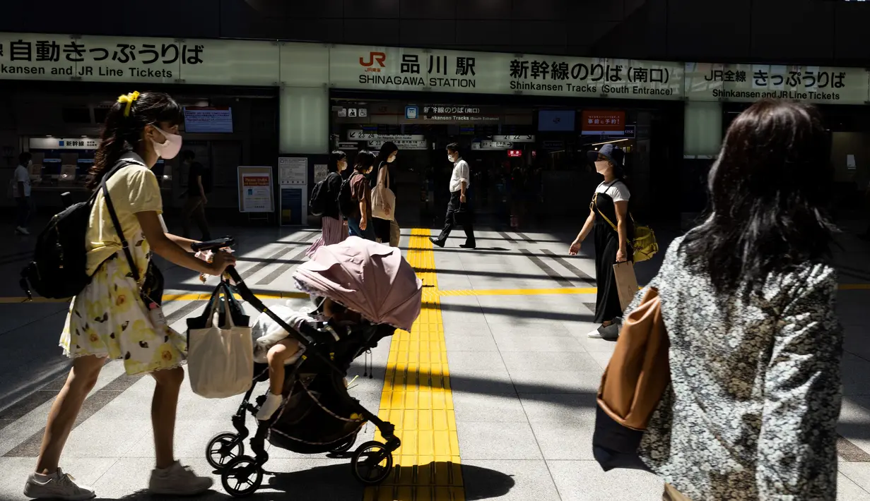 Komuter memakai masker sambil mendorong kereta bayi di stasiun kereta api di Tokyo saat keadaan darurat virus corona tetap berlaku di kota itu pada Selasa (10/8/2021).  Pemerintah Metropolitan Tokyo mengonfirmasi 2.884 kasus baru covid-19 pada Senin, 9 Agustus 2021. (Yuki IWAMURA / AFP)